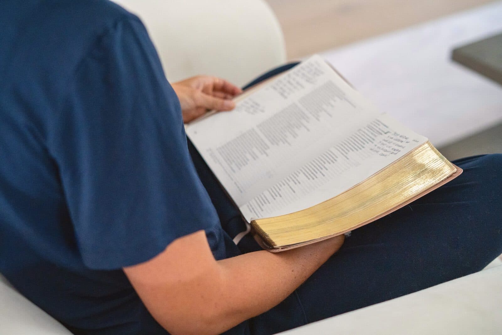 An open Bible with gold-edged pages in Danielle's lap