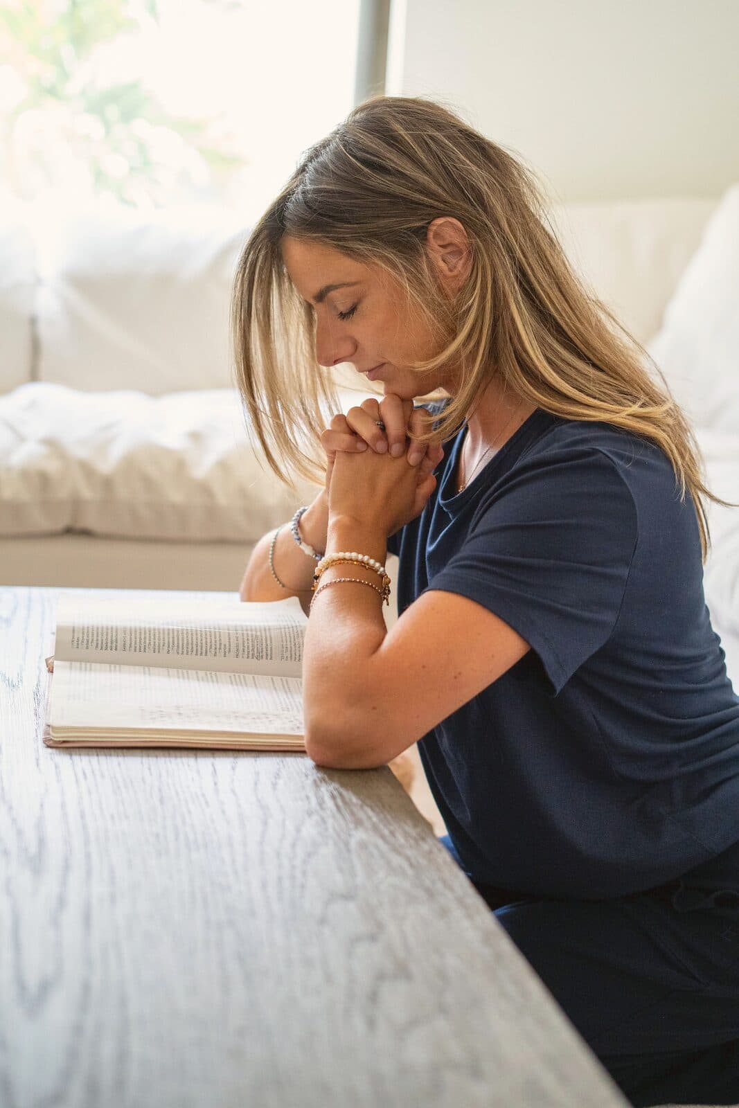 Danielle praying with her hands folded over an open Bible